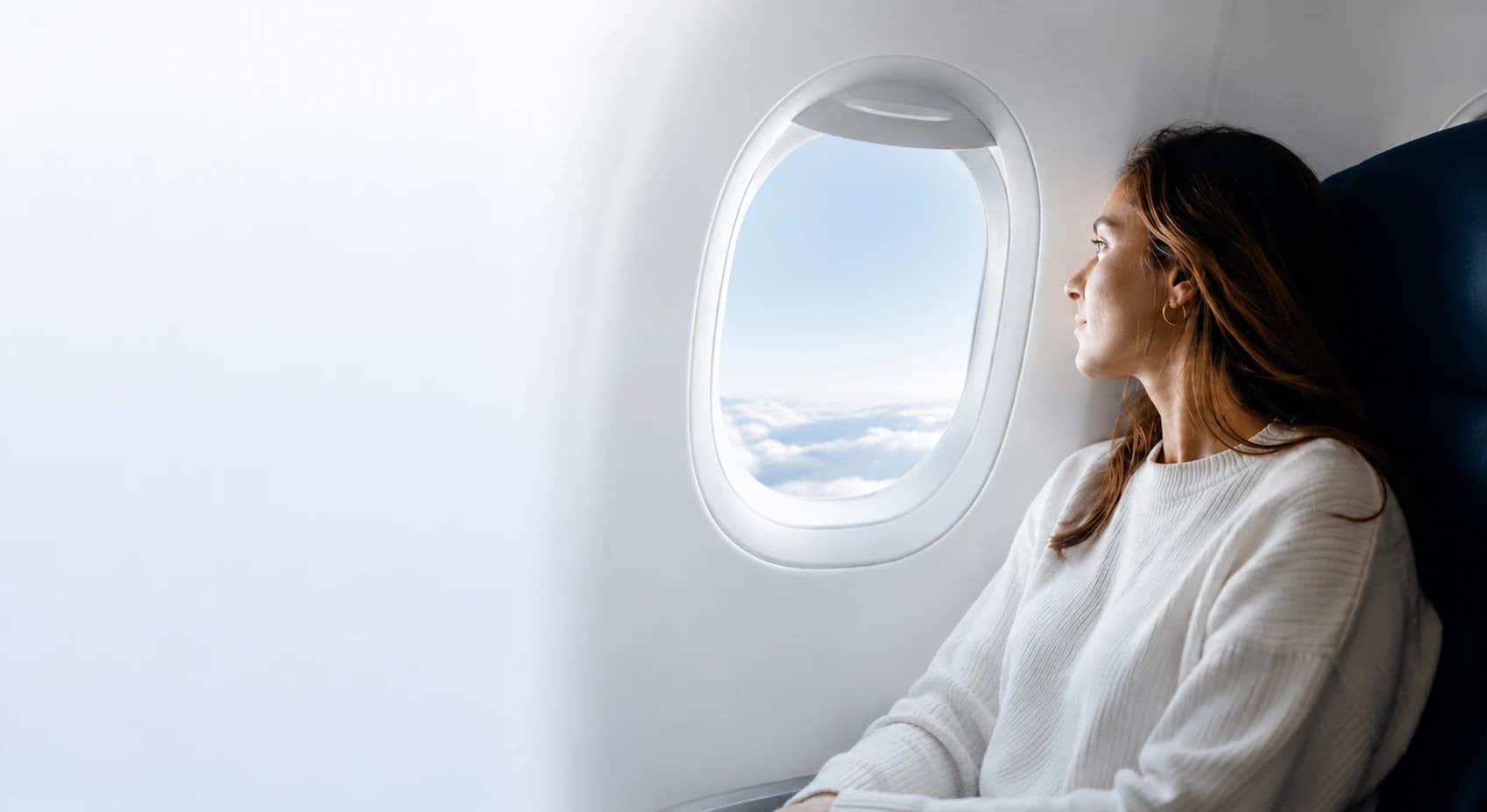 Passenger looking through the airplane window over the clouds